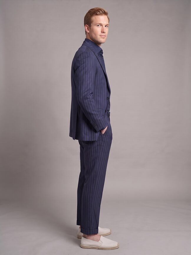 The same navy pinstripe suit from the side, showing the jacket's drape and the trouser line